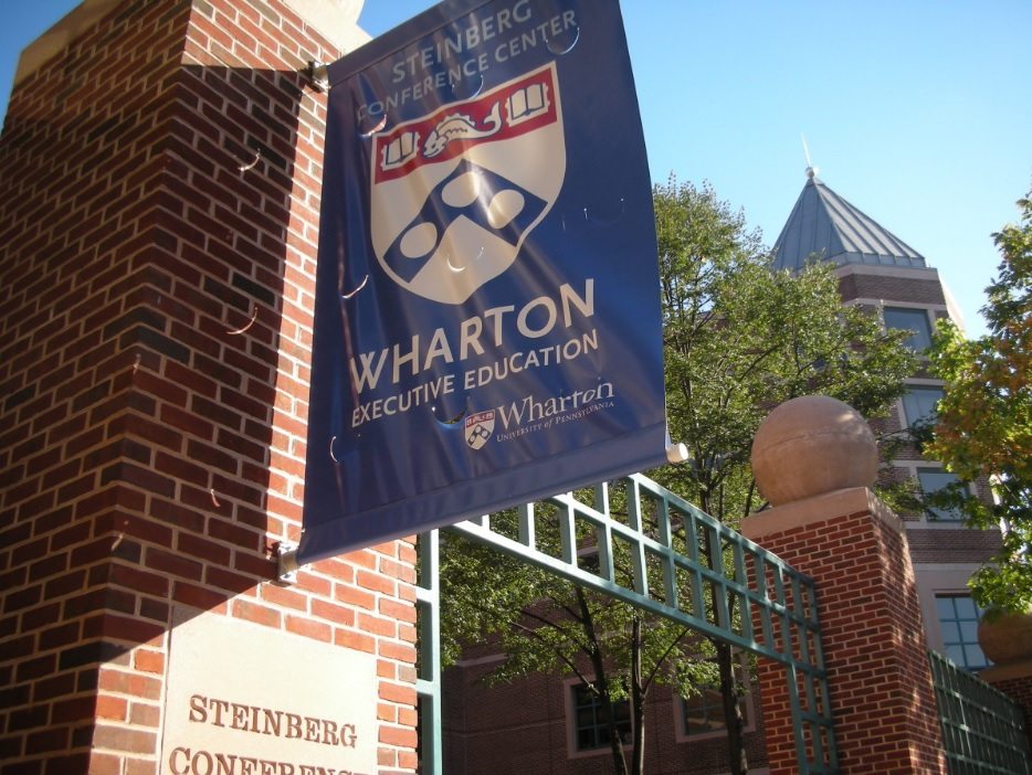 Wharton School flag on the side of a brick building