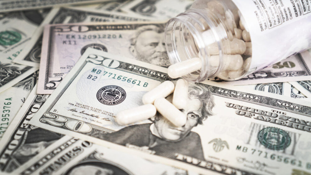 A stock image of dollar bills and an open pill bottle.