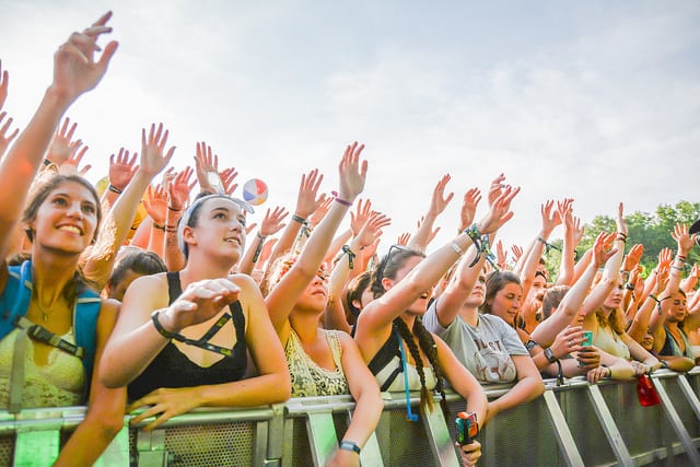 Musical festival attendees raise put their hands in the air, wave 'em like they just don't care.
