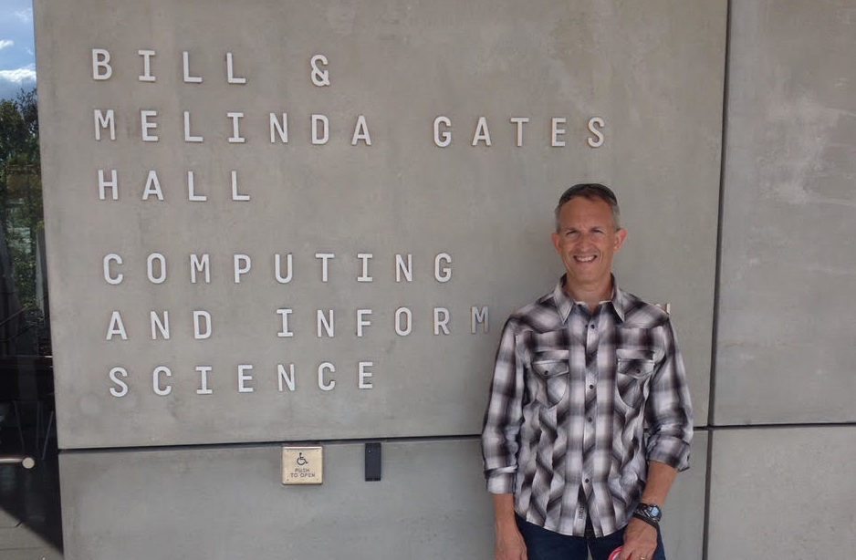 A man standing in front of a placard that reads Bill & Melinda Gates Hall..