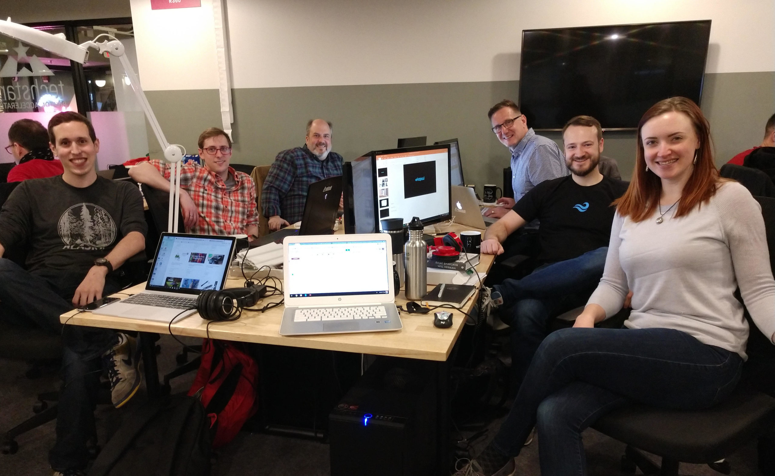 Six employees smiling for a group shot in an office setting.