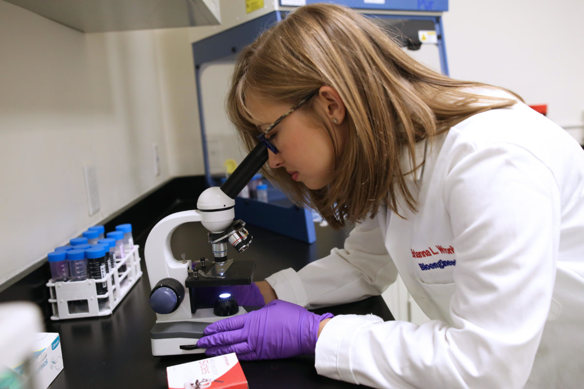 A woman looking in a microscope.