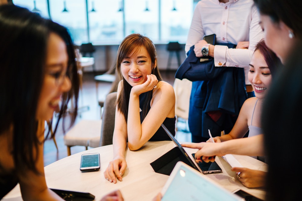 Young women at a table with digital devices