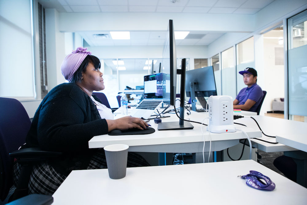 A woman and man sitting at desks in an office working on laptops.