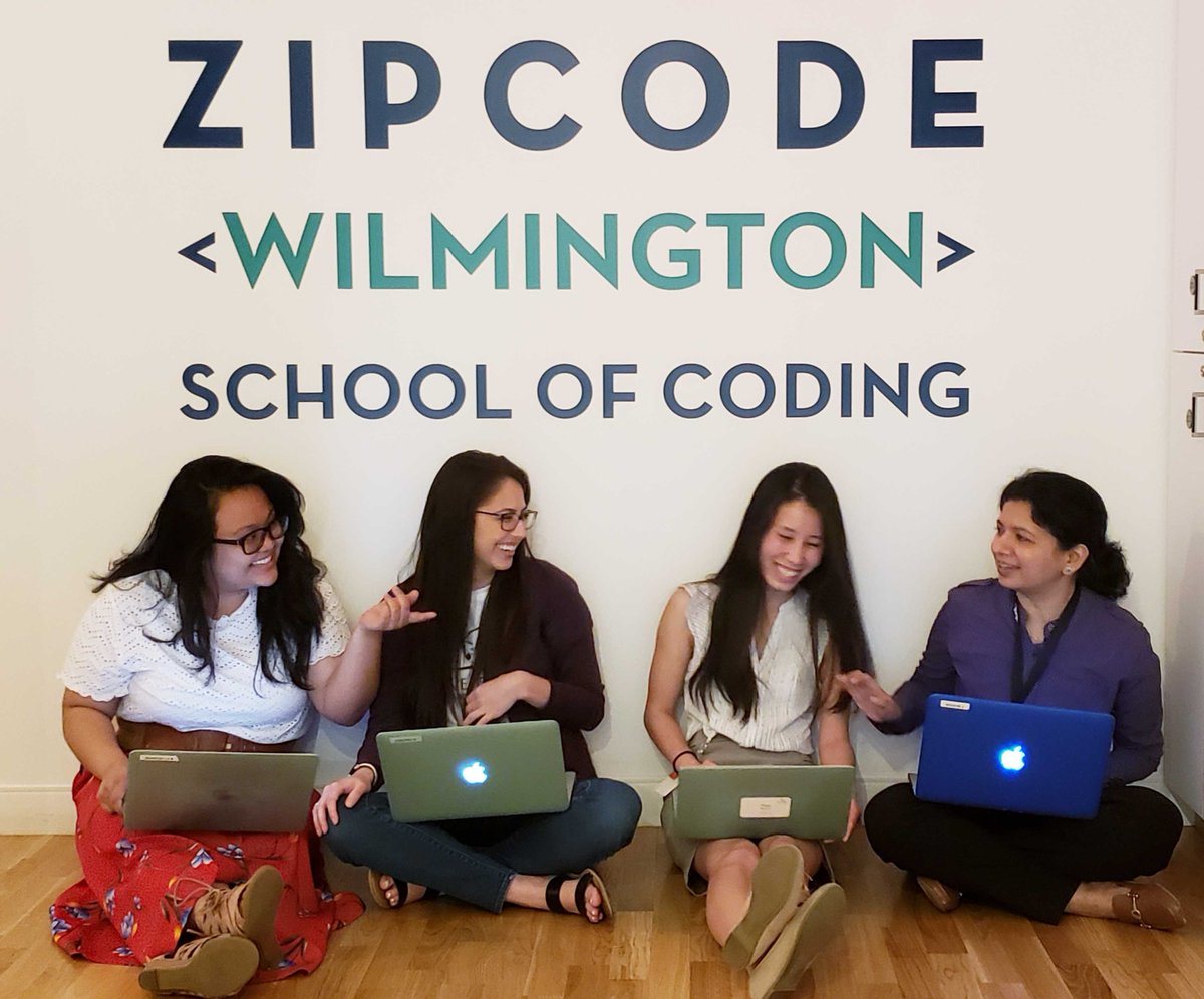 four women coders sitting in front of a Zip Code Wilmington sign