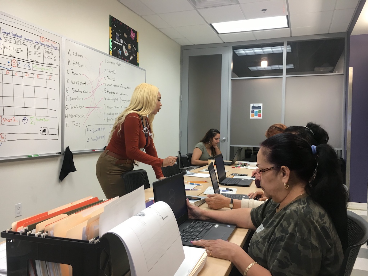 Teacher and students work at laptops