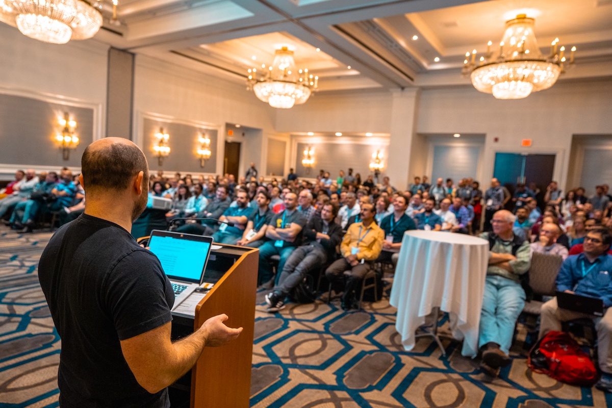 Software developers listen to a presenter in a conference room