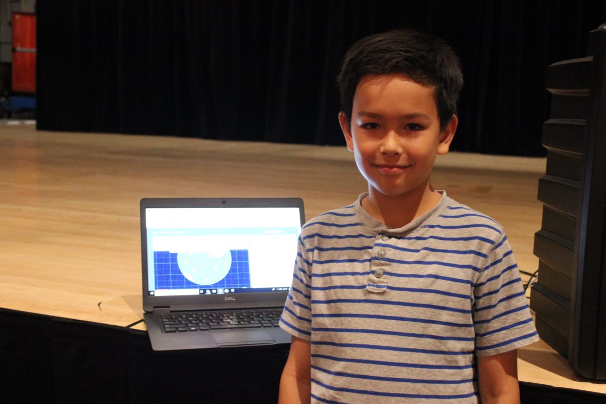 A boy stand in front of a laptop