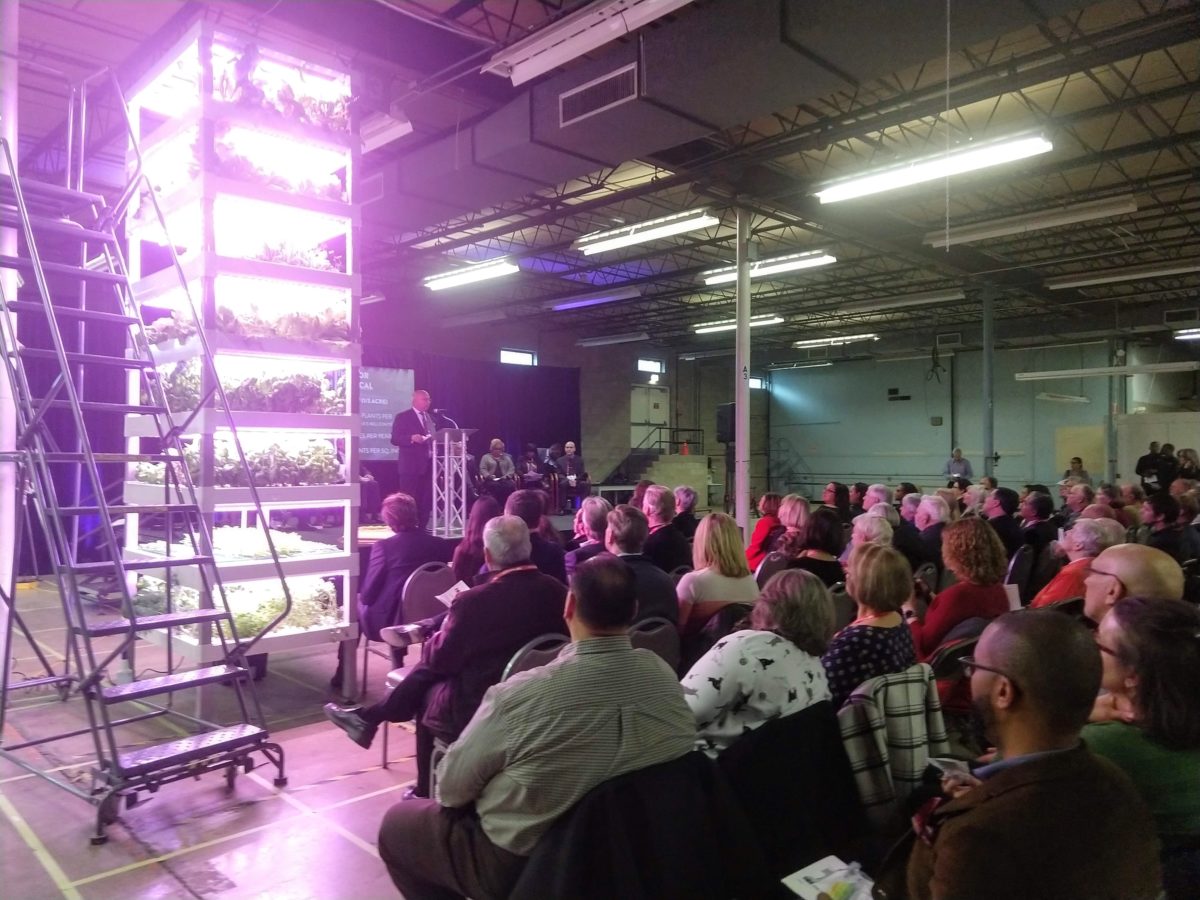 Ajit George speaks next to one of the hydroponic towers that will soon fill the warehouse space in Riverside.