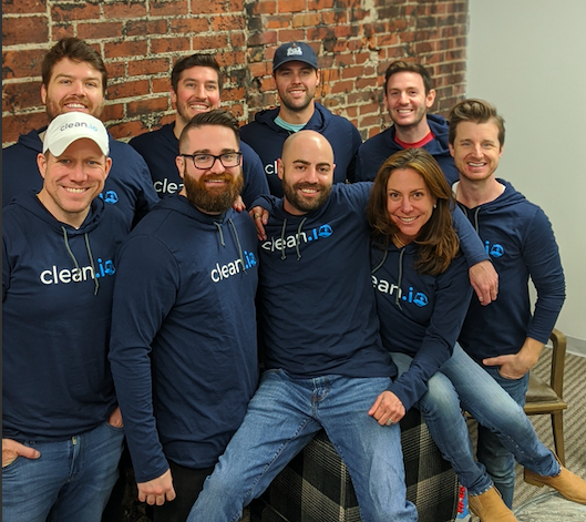People in navy sweatshirts that read "clean.io" against red brick wall