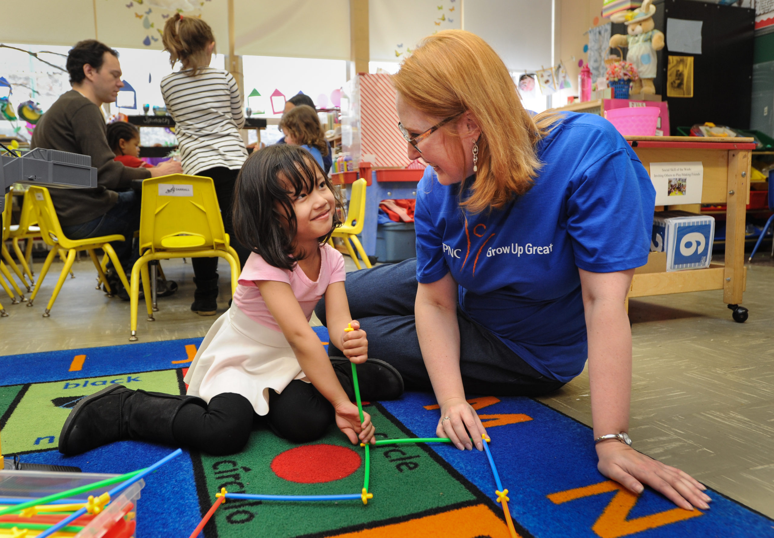Photo of a woman playing with a child in a classroom.