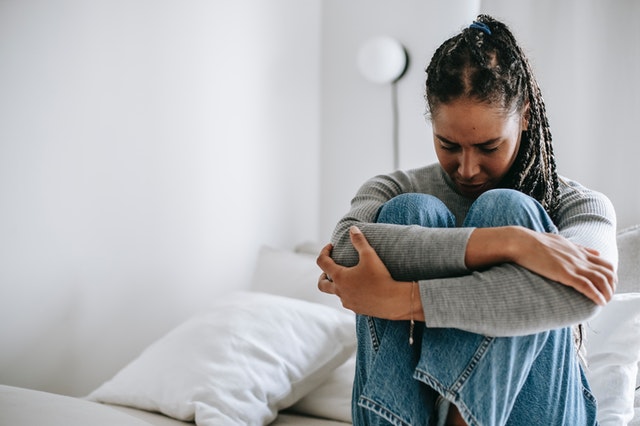 Woman sitting on a bed in pain