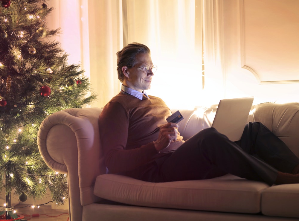 Man on laptop with credit card by Christmas tree