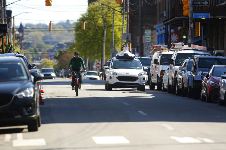 Argo AI autonomous vehicle drives along cyclist in Pittsburgh.