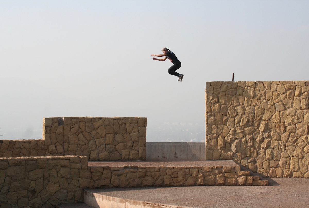 A man jumps from one tall stone pile to another