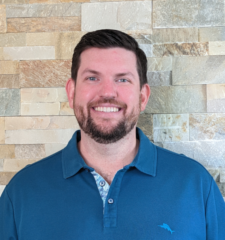 Headshot of Kent Eisenhuth wearing a blue polo shirt against a stone background.