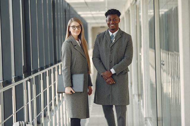 A professional woman and man standing in a hallway.