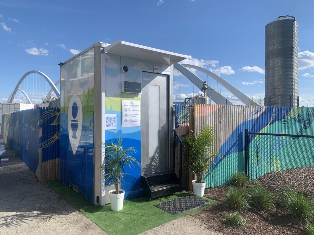 A Throne portable bathroom, featuring an overhang, steps and a blue/green/yellow design on the side