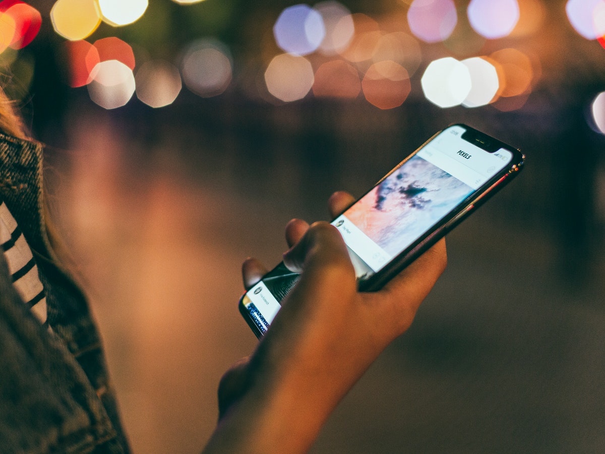 A woman holding a cell phone at night.