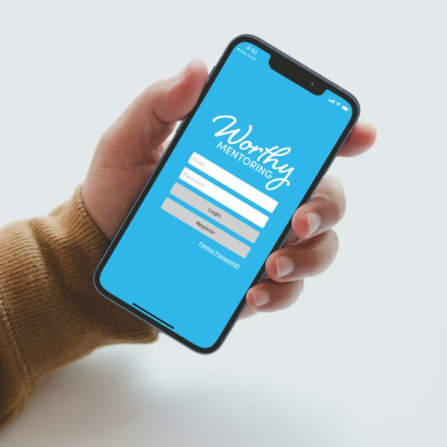 A hand holding a phone opened to the Worthy Mentoring login page