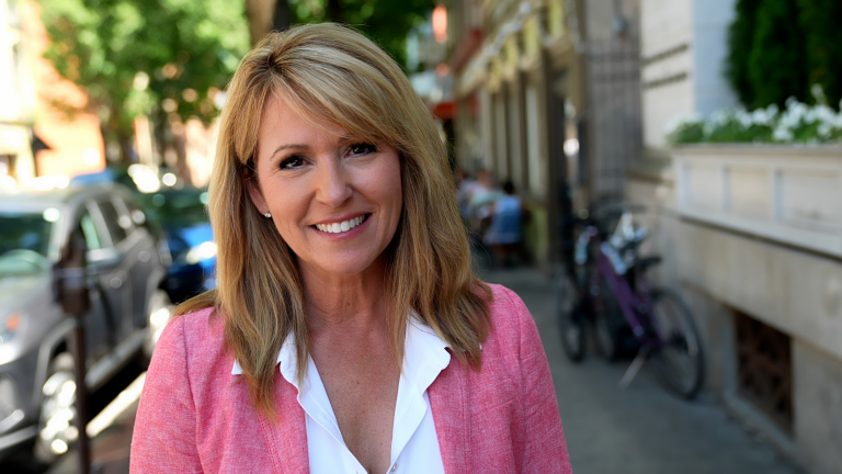 Kelly Schulz in white shirt and pink blazer on sidewalk