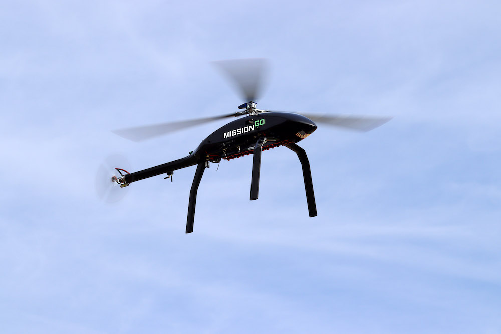 Black unmanned vehicle with white and green text against blue sky
