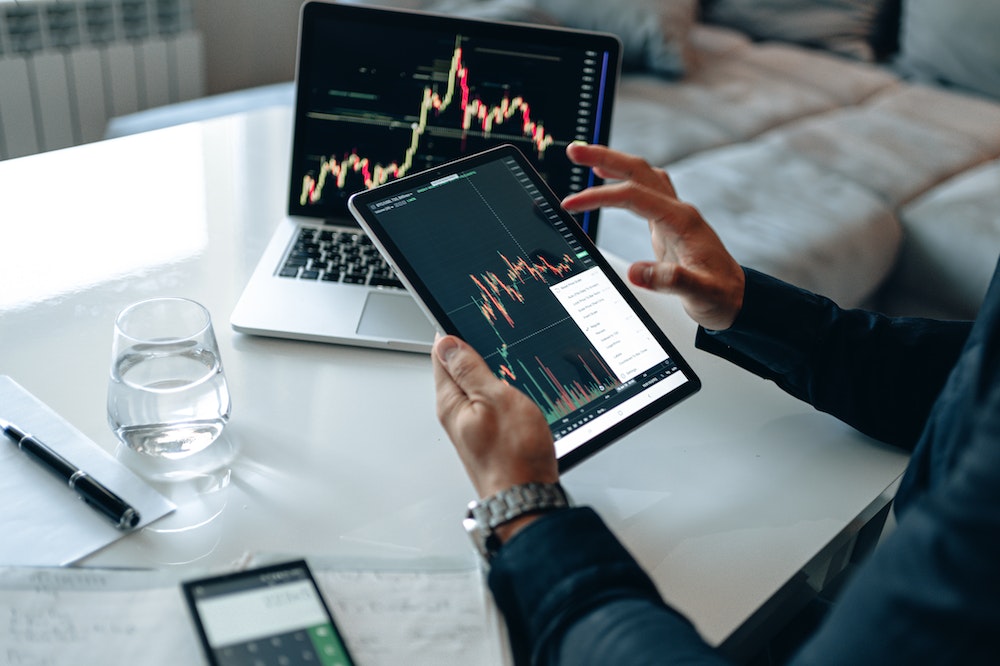 A person reading a stock market line graph on a tablet.