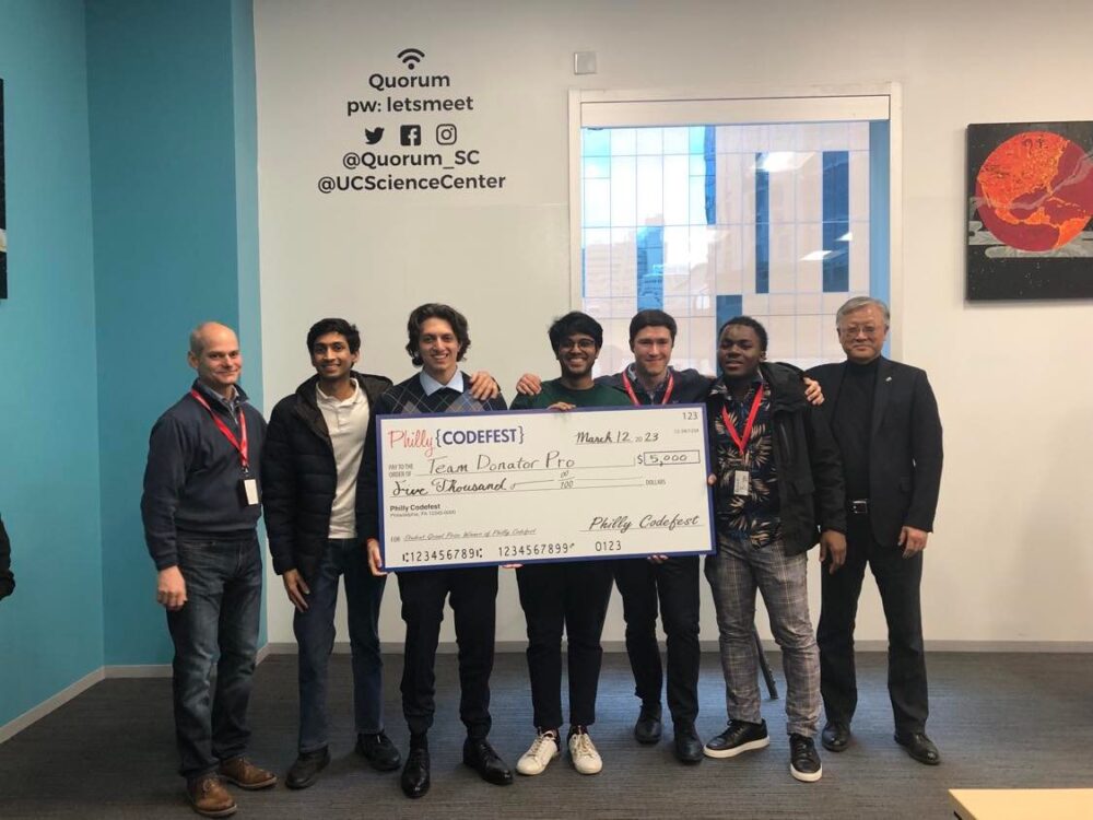 Students stand holding a big check.