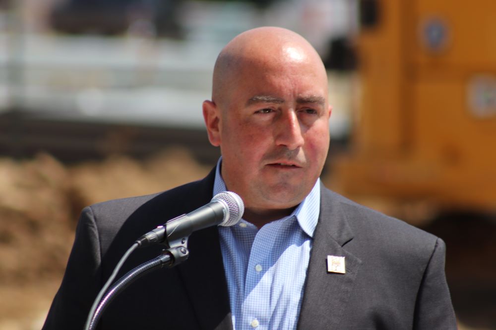 John Falcicchio speaks at a microphone during an event.
