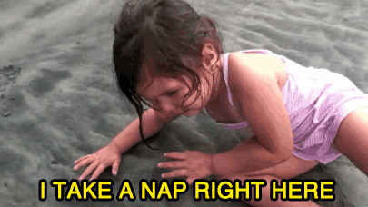 A child in a wet swimsuit lies down on the sand at the beach with the caption "I TAKE A NAP RIGHT HERE" in yellow text.