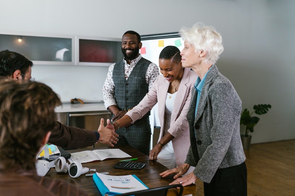 A diverse group of three founders making a deal with a VC.