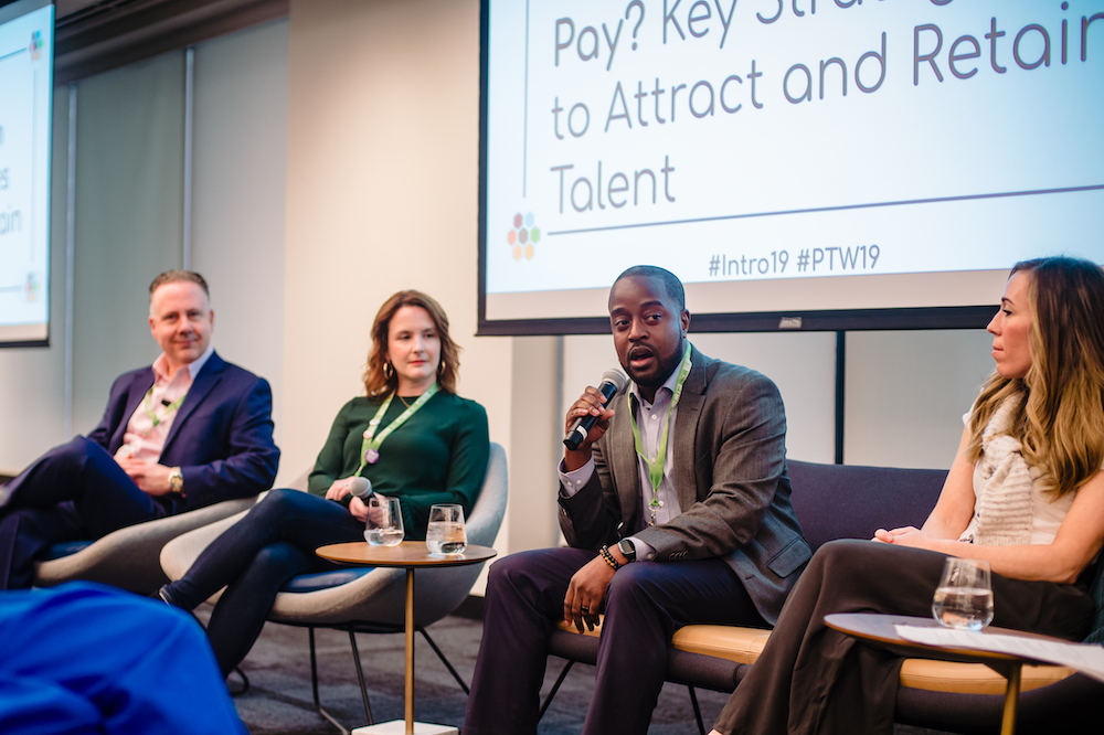 Panel discussion at a conference with four experts discussing strategies to attract and retain talent.