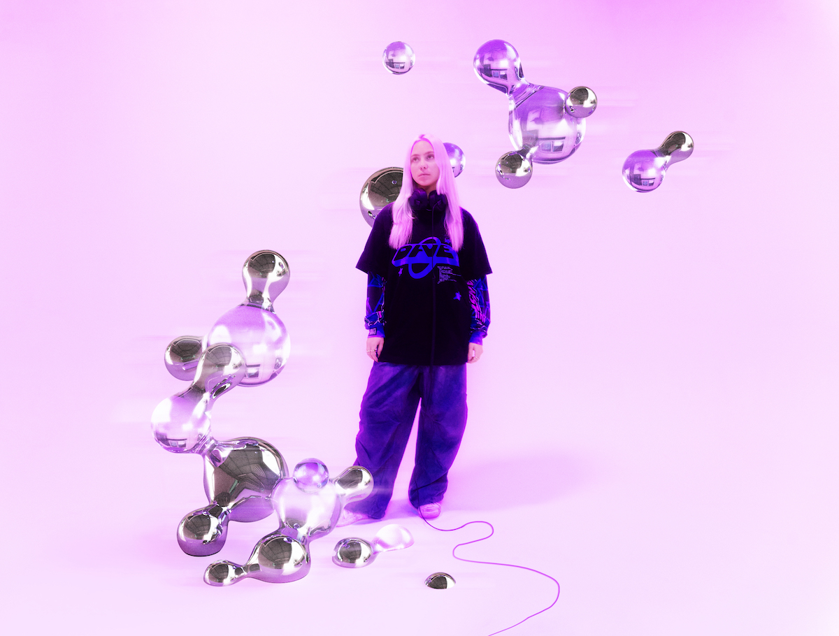 A person stands in a purple-lit space with metallic balloons floating and scattered around.