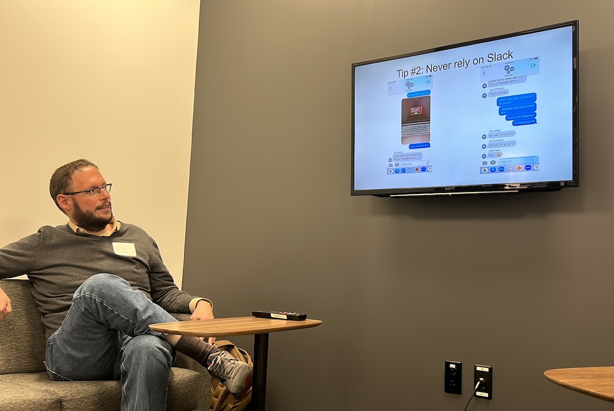 A person sitting and looking at a presentation screen with the title "tip #2: never rely on slack.