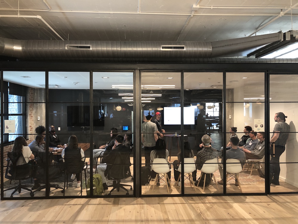 A presentation in a modern office conference room viewed through glass walls.