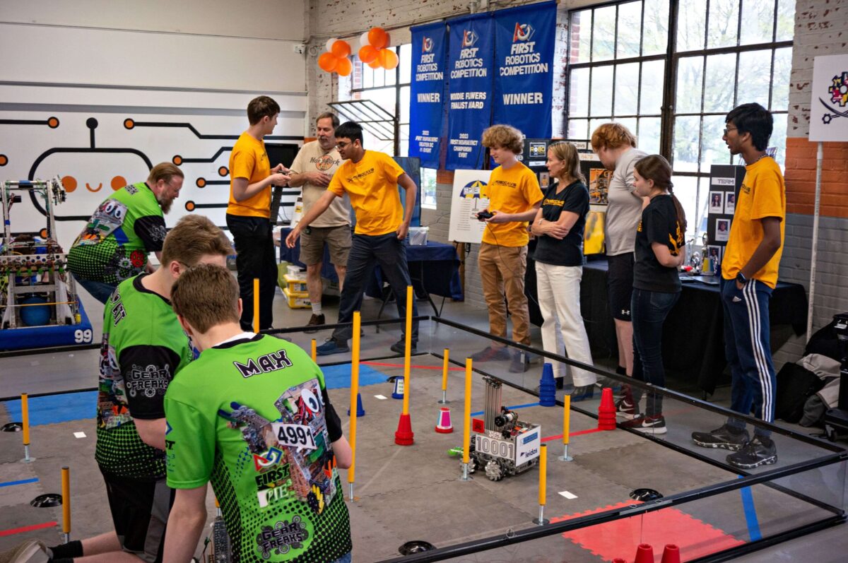 Students and mentors engaged in a robotics competition in a workshop setting.