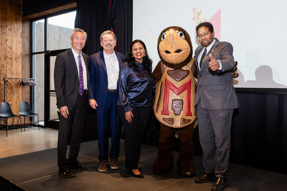 Four individuals and a person in a horse mascot costume posing for a photo at an event.