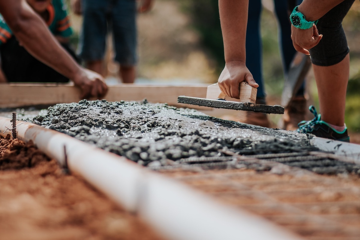Workers smooth out concrete on a construction site.