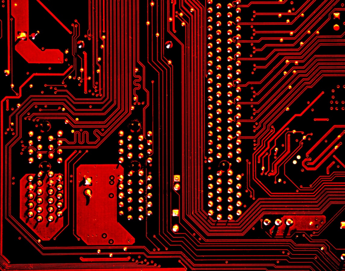 Close-up of a red circuit board with gold and silver connections.