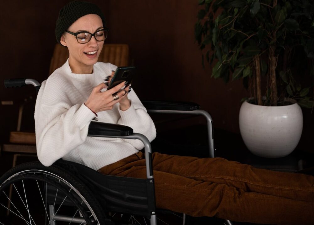 Person in a wheelchair using a smartphone with a smile.