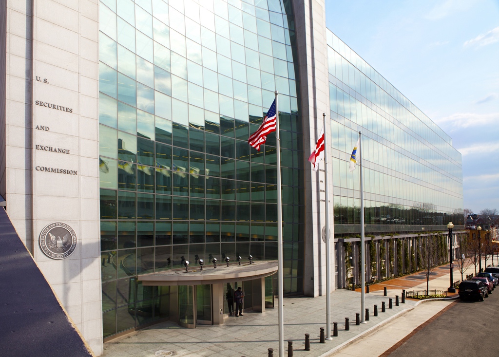 A stately, glass-paneled building with American flags out front.