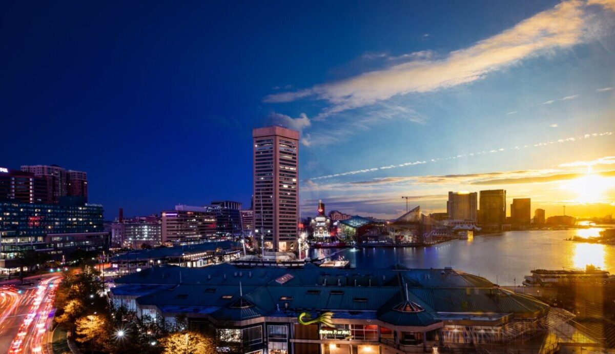 Baltimore skyline against sky ranging from sunlit yellow to dark blue