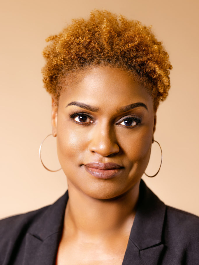An african-american woman wearing a black jacket and hoop earrings.