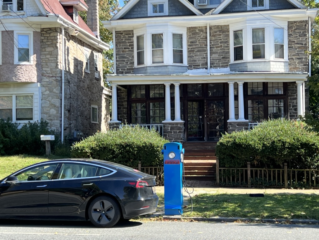A tesla parked in front of a house.