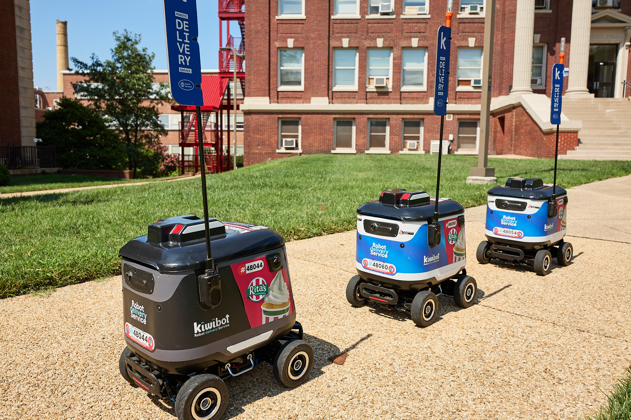 Three robots on a sidewalk in front of a building.