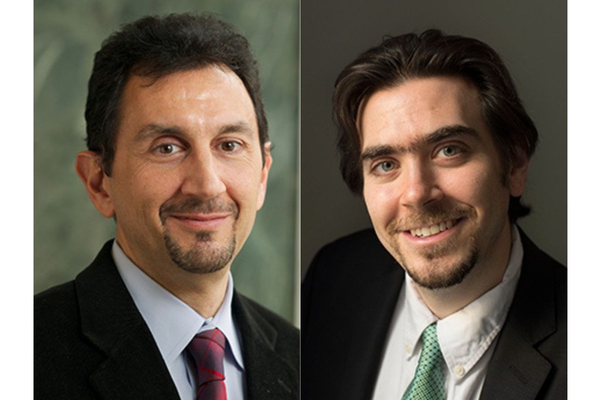 Two men in suits and ties are posing for a photo.