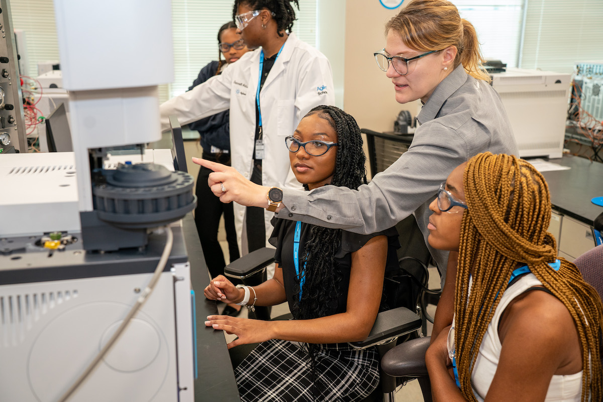 A group of women working on a machine in a lab.