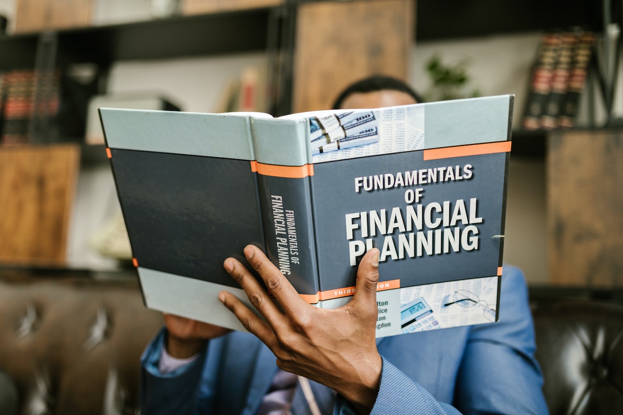 A man holding a book with the title fundamentals of financial planning.