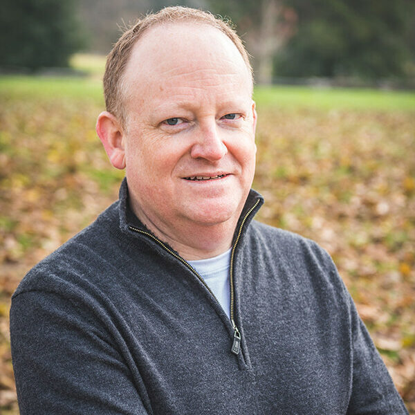 A man in a black sweater standing in a field.