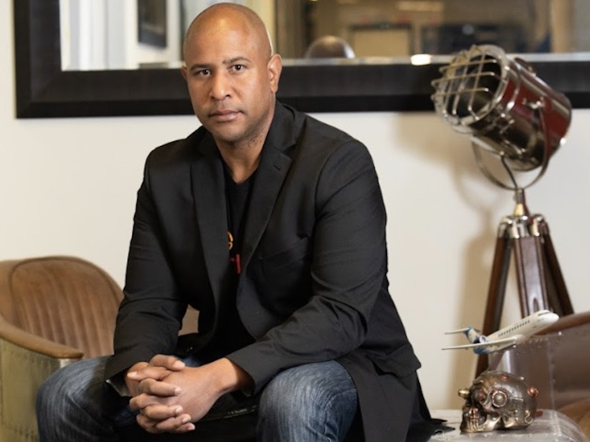 A man in a black jacket sitting on a chair.